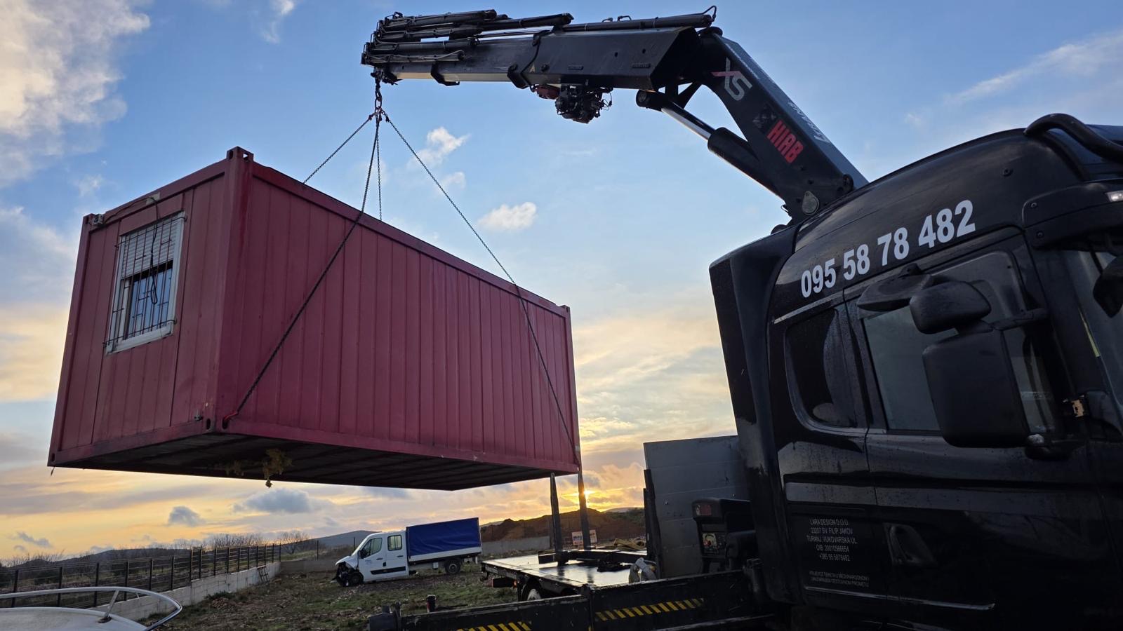 Dizalica L-trans podiže crveni kontejner u zalazak sunca